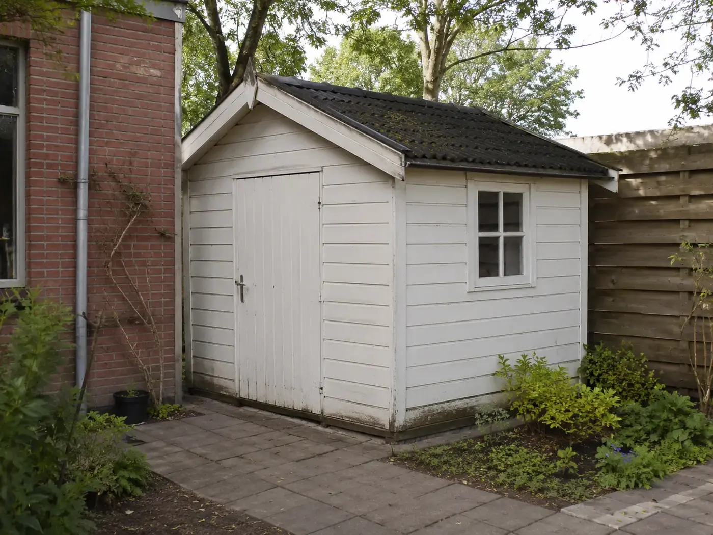 Witte schuur naast een woning die leeggehaald wordt