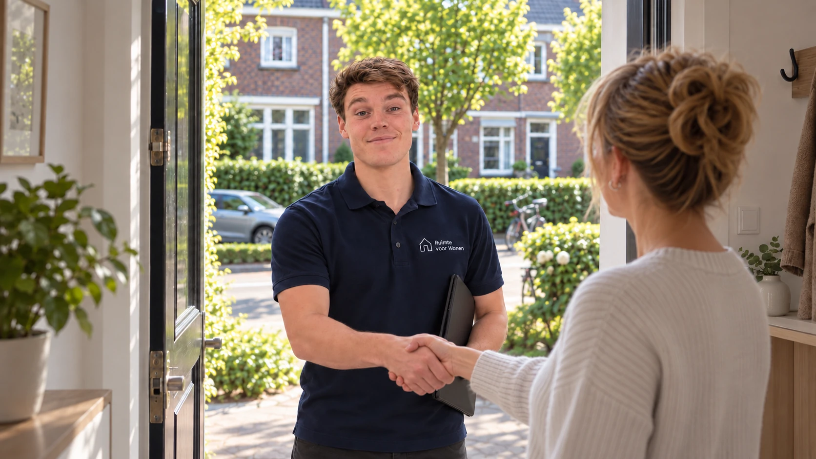 Medewerker van Ruimte voor Wonen schudt hand met klant aan de deur