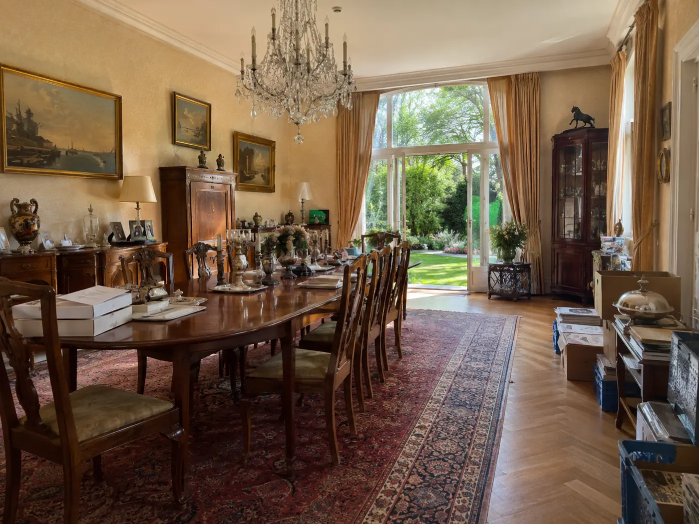 Ruime eetkamer vóór de ontruiming, met klassieke inrichting, grote eettafel, kasten en losse spullen.