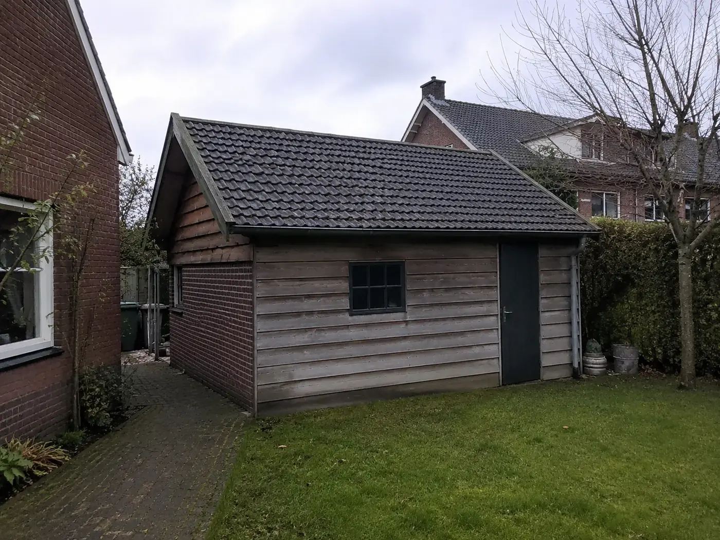 Houten schuur met pannendak in de achtertuin die leeggehaald wordt
